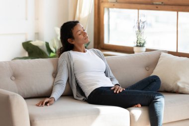 Siyah milenyum kadını oturma odasında kanepede oturur.