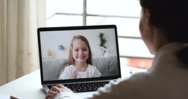 Dizüstü bilgisayarda anaokulu öğrencisine öğretmenlik yapan bayan öğretmen videosu.