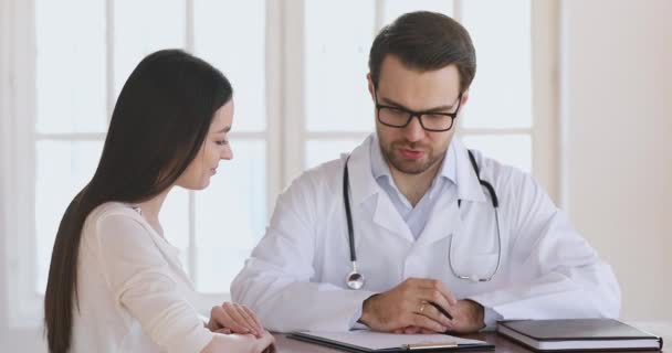 Professionele mannelijke arts bespreken medische verzekering contractgegevens met patiënt. — Stockvideo