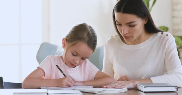 Mère qualifiée tuteur enseignant la petite fille enfant écriture . — Video