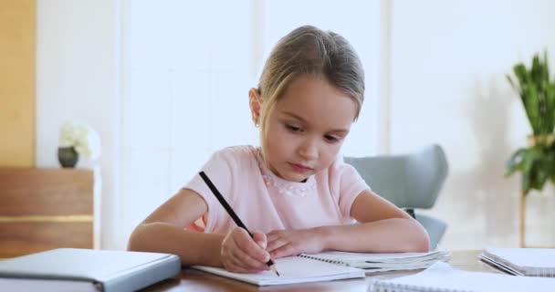 Focused cute little kid girl doing homework alone. — Stock Video