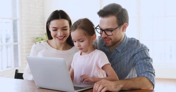 Lächelnde Eltern unterrichten kleine intelligente Mädchen mit Laptop. — Stockvideo
