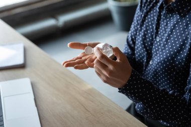 Kadın çalışan, antibakteriyel jelle ellerini sterilize ediyor.