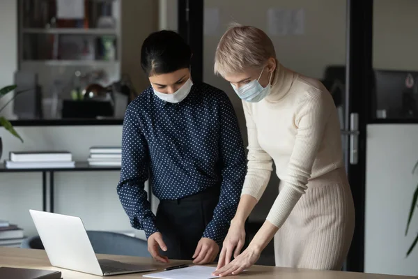 Female colleagues in face masks work in office — Stock Photo, Image