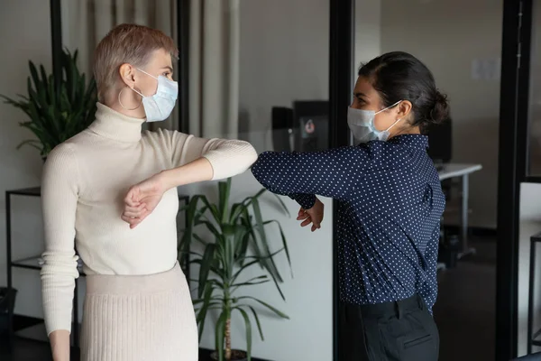 Female colleagues greeting in office touching elbows — Stock Photo, Image