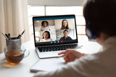 Kadın video konferansı yoluyla çok ırklı öğrencilerle evde çalışıyor.