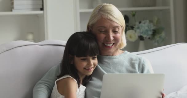 Gelukkig middelbare leeftijd vrouw met behulp van computer met kleindochter. — Stockvideo