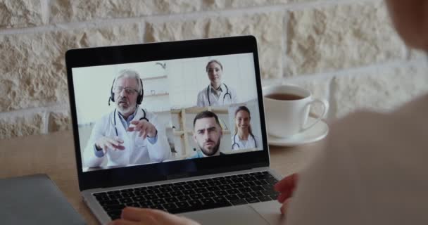 Přes rameno pohled na ošetřovatelku, jak mluví s doktory videokonference — Stock video