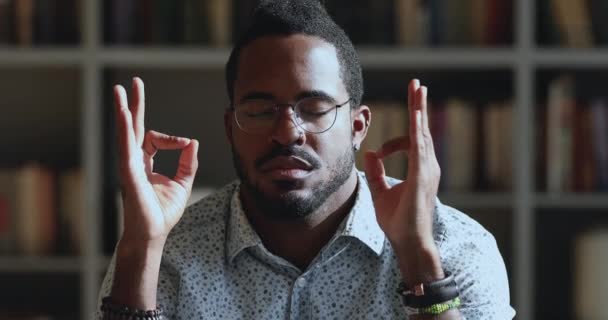 Friedlicher junger Mann afrikanischer Herkunft reduziert Stress bei der Arbeit — Stockvideo