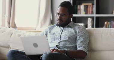 Konsantre genç Afrikalı etnik adam internette sörf bilgilerini kontrol ediyor.