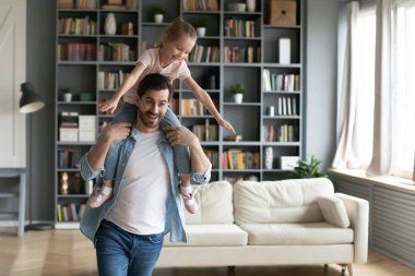 Neşeli baba omuzlarında küçük kız içeride eğleniyor.