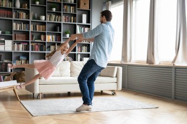 Baba el ele tutuşup kızı döndürüyor evde eğleniyor.