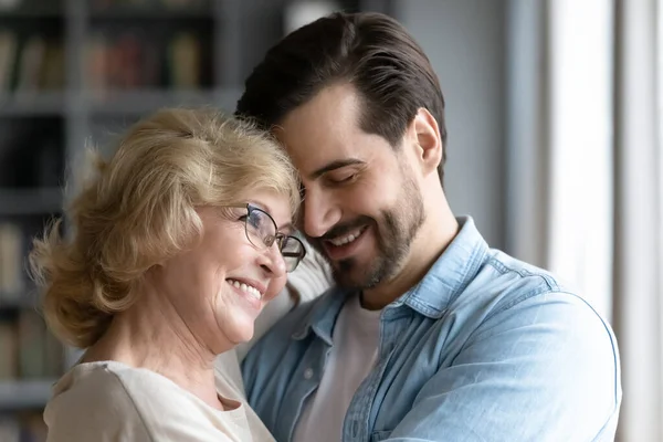 Millennial fils et mère âgée étreignant debout à l'intérieur — Photo