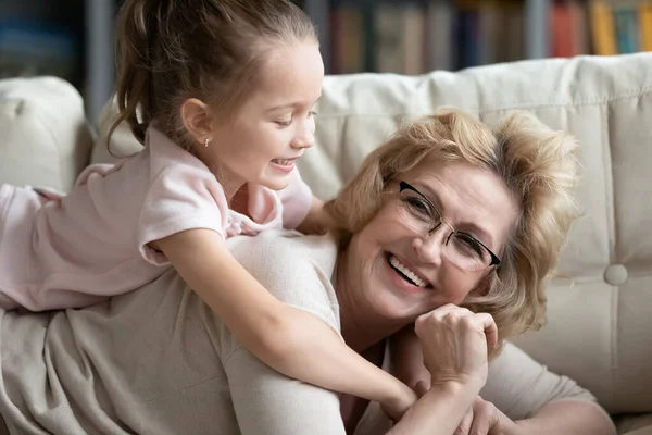 Nonna e nipote sdraiate sul divano che si divertono a casa — Foto Stock