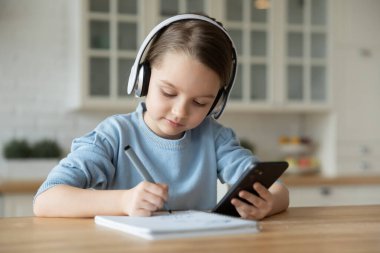 Küçük kız evde akıllı telefon kullanarak çevrimiçi çalışıyor.