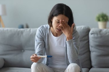 Hamilelik testinden memnun olmayan mutsuz kadın alnına dokunuyor.