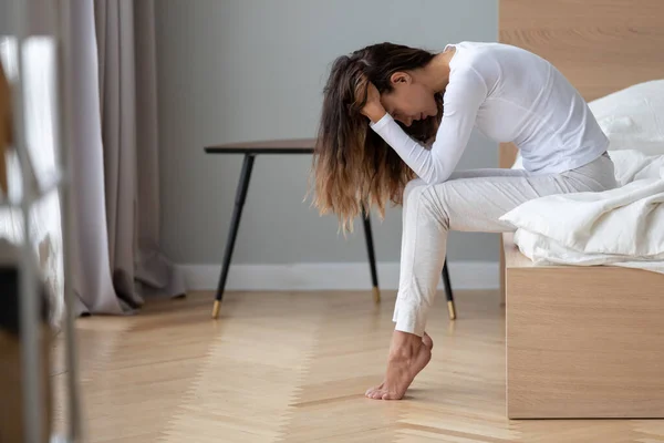 Depressive junge Frau sitzt allein im Bett und denkt über Probleme nach — Stockfoto