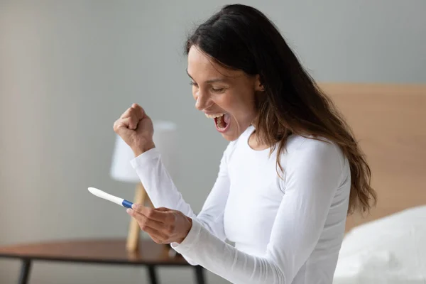Mujer emocionada gritando de alegría, sosteniendo la prueba de embarazo, sintiéndose feliz — Foto de Stock