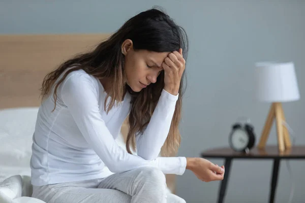 Ongelukkige vrouw die op bed zit, zich depressief voelt, denkt aan problemen — Stockfoto