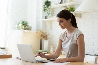 Hesaplama için hesap makinesi ve laptop kullanan mutlu genç ve çekici bir kadın..
