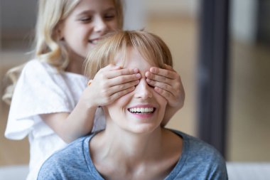Şirin kız, gülümseyen anneye sürpriz yaparak gözlerini kapatıyor..
