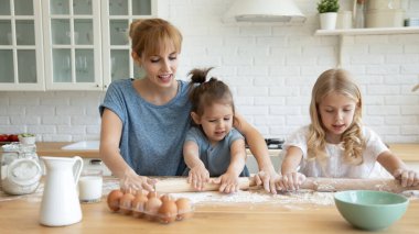 Gülümseyen anne küçük kız kardeşlere para dağıtmayı öğretiyor..