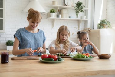 Bakıcı anne iki küçük çocuğa bıçak kullanmayı öğretiyor..