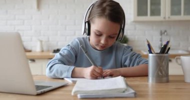 Kulaklık takıp evde ders çalışan sevimli bir kız.