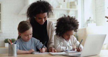 Afrikalı anne, öğretmen iki melez kızın birlikte okumasına yardım ediyor.