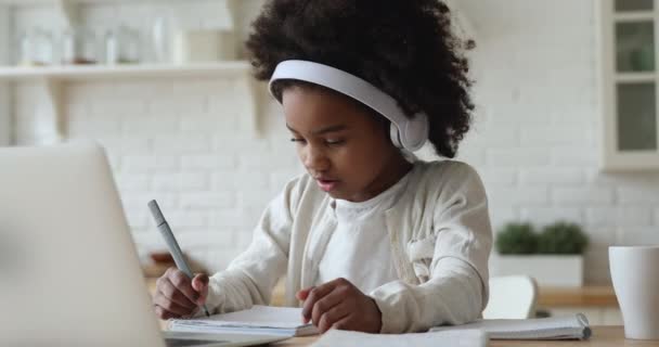 Afro fille américaine enfant portant des écouteurs étudier en ligne de la maison — Video