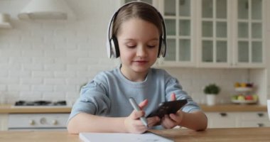 Kulaklık takan çocuk özel hocasıyla cep telefonuyla ders çalışıyor.