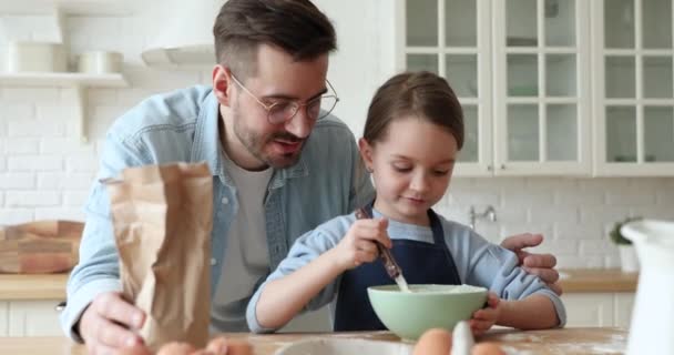 Zorgvuldige vader onderwijs kind dochter leren maken deeg in de keuken — Stockvideo
