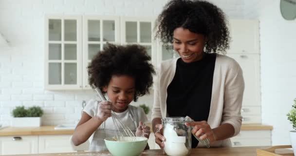 Szczęśliwy afro-amerykański młody mama i słodkie dziecko córka whisking ciasto — Wideo stockowe