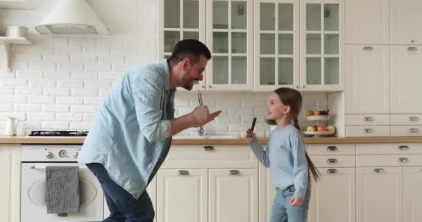 Funny happy father and kid daughter singing together in kitchen — Stock Video