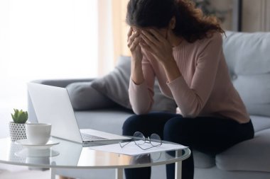 Stresli, mutsuz, genç bir kadın bilgisayarın aşırı çalışmasından yorgun düşüyor..