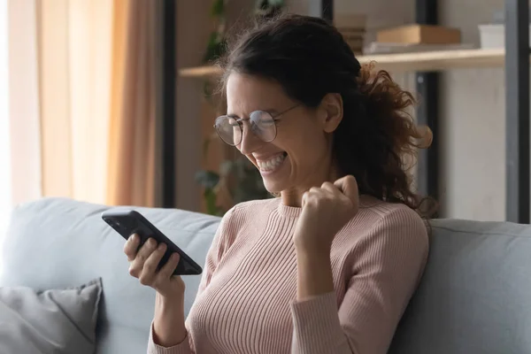 Young woman looking at mobile screen, amazed by good news.