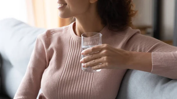 Jonge glimlachende vrouw met een glas fris water, wegkijkend. — Stockfoto