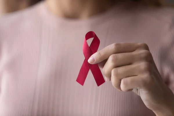 Close up focus on red ribbon in female hands. — Stock Photo, Image