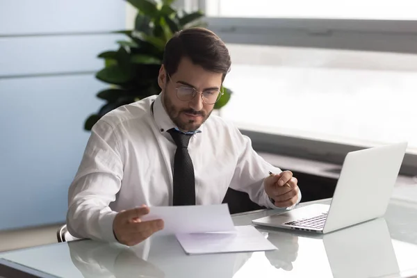 Joven empresario serio leyendo documento y analizando estadísticas . — Foto de Stock