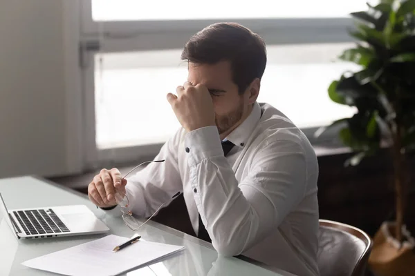 Empresario ocupado quitándose las gafas, sufriendo de síndrome de ojos secos . — Foto de Stock