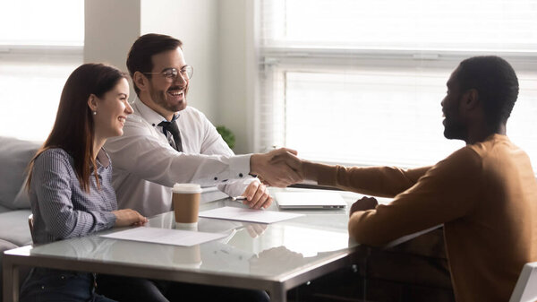Happy african american candidate shaking hands with businessman recruiter.