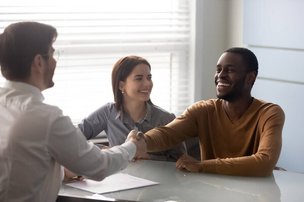 Smiling african american husband shaking hands with businessman.
