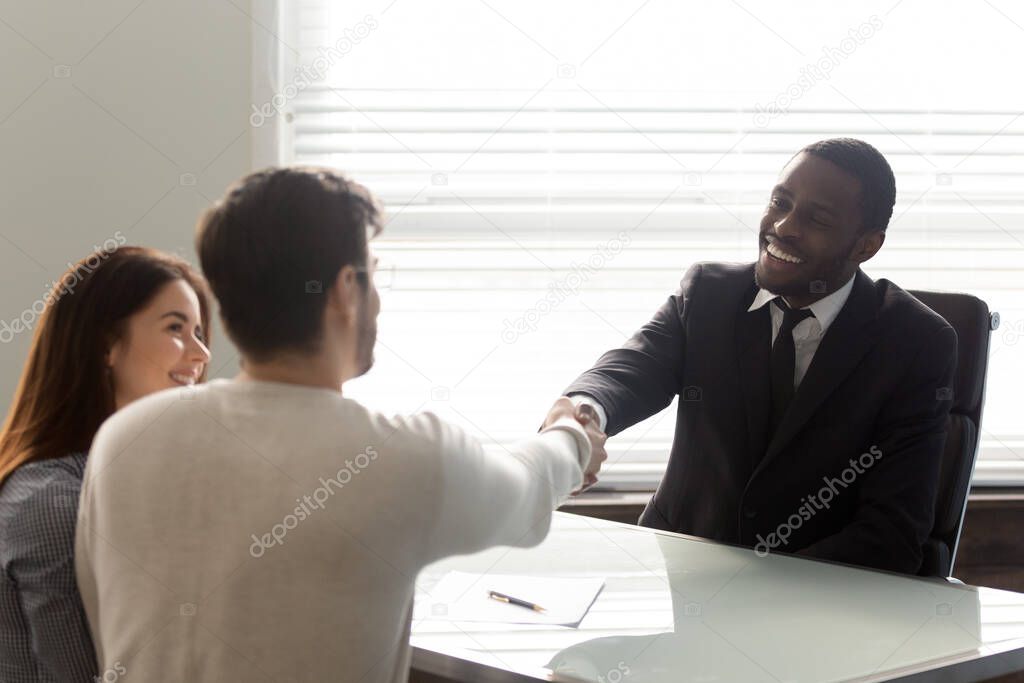 Happy african american businessman shaking hands with man.