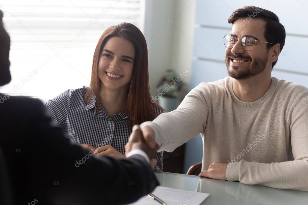 Young successful couple, man and woman shaking hands with businessman.