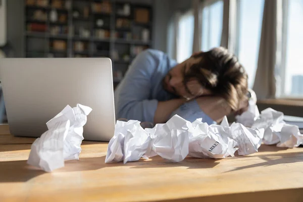Unavený přepracovaný podnikatel spí za psacím stolem pokryté zmačkané papíry — Stock fotografie