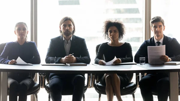 Vier selbstbewusste Manager sitzen hintereinander am Tisch — Stockfoto