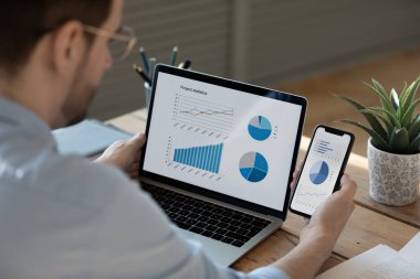 Bilgisayarda ve telefonda istatistiklerle çalışan işadamını kapat