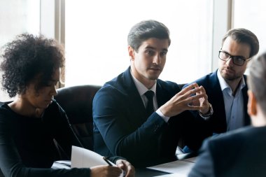 Çeşitli iş adamları toplantı odasında proje stratejisini tartışıyor