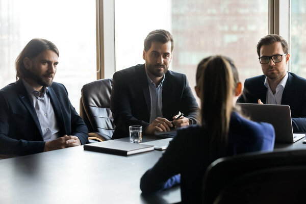 Три серьезных менеджера рассматривают кандидата на встрече
