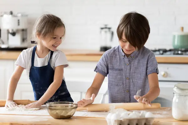 Overblij kleine kinderen broers en zussen spelen met bloem in de keuken. — Stockfoto